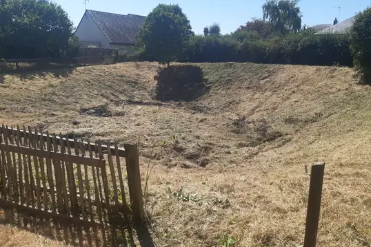 Terrain délimité par une clôture en bois après débroussailage.